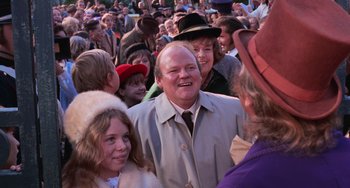 Movie still from “Willy Wonka & the Chocolate Factory” (1971), directed by Mel Stuart – A crowd of people standing around each other in the street; Medium shot, Over the shoulder angle