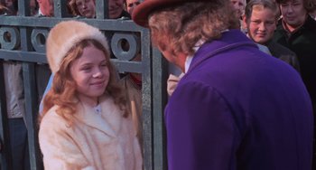 Movie still from “Willy Wonka & the Chocolate Factory” (1971), directed by Mel Stuart – A girl in a fur coat is talking to a man in a purple jacket; Medium shot, Over the shoulder angle