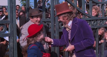 Movie still from “Willy Wonka & the Chocolate Factory” (1971), directed by Mel Stuart – A young girl in a red hat and a purple jacket and a man in a purple jacket and a man in a red hat; Medium shot, Over the shoulder angle