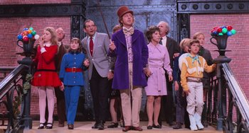 Movie still from “Willy Wonka & the Chocolate Factory” (1971), directed by Mel Stuart – A group of people standing around a man in a purple coat; Wide shot, Low angle