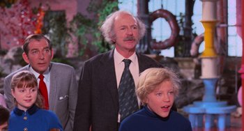 Movie still from “Willy Wonka & the Chocolate Factory” (1971), directed by Mel Stuart – An older man and a young boy are standing together; Medium shot, Low angle