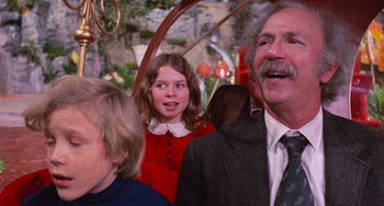Movie still from “Willy Wonka & the Chocolate Factory” (1971), directed by Mel Stuart – A man and a woman and a little girl in front of an umbrella; Close Up shot, Over the shoulder angle