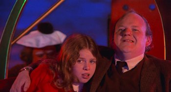 Movie still from “Willy Wonka & the Chocolate Factory” (1971), directed by Mel Stuart – A young girl and an older man are sitting together; Medium shot, Low angle