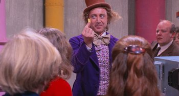 Movie still from “Willy Wonka & the Chocolate Factory” (1971), directed by Mel Stuart – A man dressed as willy wonka is holding a piece of candy; Close Up shot, Over the shoulder angle