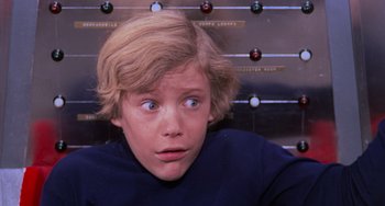 Movie still from “Willy Wonka & the Chocolate Factory” (1971), directed by Mel Stuart – A young man with blonde hair and blue eyes stares into the camera; Close Up shot, Low angle