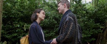 Movie still from “Winnie the Pooh: Blood and Honey” (2023), directed by Rhys Frake-Waterfield – A man and a woman holding hands in front of trees; Medium shot, Over the shoulder angle