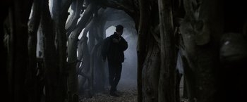 Movie still from “Winnie the Pooh: Blood and Honey” (2023), directed by Rhys Frake-Waterfield – A man walking through a tunnel in the woods; Wide shot, Low angle