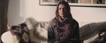 Movie still from “Winnie the Pooh: Blood and Honey” (2023), directed by Rhys Frake-Waterfield – A woman sitting on a couch in front of a picture; Close Up shot, Low angle