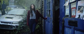 Movie still from “Winnie the Pooh: Blood and Honey” (2023), directed by Rhys Frake-Waterfield – A woman standing in front of a blue door; Medium shot, Low angle