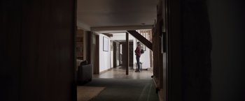 Movie still from “Winnie the Pooh: Blood and Honey” (2023), directed by Rhys Frake-Waterfield – A person standing in a room with a chair; Wide shot, Low angle