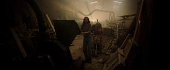 Movie still from “Winnie the Pooh: Blood and Honey” (2023), directed by Rhys Frake-Waterfield – A woman standing in an industrial setting holding a hammer; Wide shot, Low angle