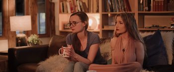 Movie still from “Winnie the Pooh: Blood and Honey” (2023), directed by Rhys Frake-Waterfield – Two women sitting on a couch holding a coffee mug; Medium shot, Over the shoulder angle