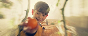 Movie still from “Winnie the Pooh: Blood and Honey” (2023), directed by Rhys Frake-Waterfield – A boy holding an orange in his hand; Extreme Close Up shot, Over the shoulder angle