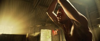 Movie still from “Winnie the Pooh: Blood and Honey” (2023), directed by Rhys Frake-Waterfield – A shirtless man standing in a room next to chains; Close Up shot, Low angle