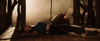 Movie still from “Winnie the Pooh: Blood and Honey” (2023), directed by Rhys Frake-Waterfield – A woman laying on the ground chained to a rope; Medium shot, High angle