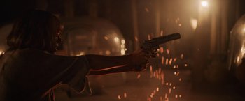 Movie still from “Winnie the Pooh: Blood and Honey” (2023), directed by Rhys Frake-Waterfield – A person holding a gun in the dark with sparks in the background; Medium shot, Low angle