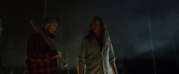 Movie still from “Winnie the Pooh: Blood and Honey” (2023), directed by Rhys Frake-Waterfield – A man and a woman holding a baseball bat in a dark room; Medium shot, Over the shoulder angle