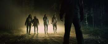 Movie still from “Winnie the Pooh: Blood and Honey” (2023), directed by Rhys Frake-Waterfield – A group of people walking through a forest at night; Wide shot, Low angle