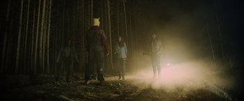 Movie still from “Winnie the Pooh: Blood and Honey” (2023), directed by Rhys Frake-Waterfield – A group of people standing in the woods at night; Wide shot, Low angle