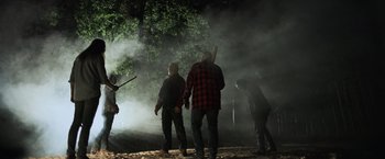 Movie still from “Winnie the Pooh: Blood and Honey” (2023), directed by Rhys Frake-Waterfield – A group of people standing next to each other in the woods; Wide shot, Low angle