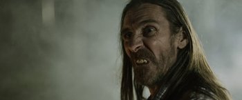 Movie still from “Winnie the Pooh: Blood and Honey” (2023), directed by Rhys Frake-Waterfield – A person with long hair and a beard; Close Up shot, Over the shoulder angle