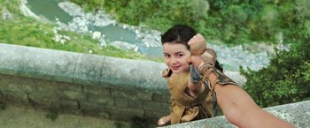 Movie still from “Wonder Woman” (2017), directed by Patty Jenkins – A young boy in a costume is holding a rope; Medium shot, Overhead angle