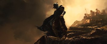 Movie still from “Wonder Woman” (2017), directed by Patty Jenkins – A man standing on top of a mountain with a helmet on; Wide shot, Low angle