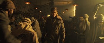 Movie still from “Wonder Woman” (2017), directed by Patty Jenkins – A man wearing a jacket and gloves in a room; Medium shot, Over the shoulder angle