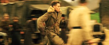 Movie still from “Wonder Woman” (2017), directed by Patty Jenkins – A young man in an army jacket running in the street; Medium shot, Low angle