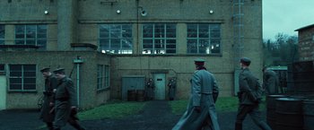 Movie still from “Wonder Woman” (2017), directed by Patty Jenkins – A man in a uniform walking in front of a building; Extreme Wide shot, Low angle