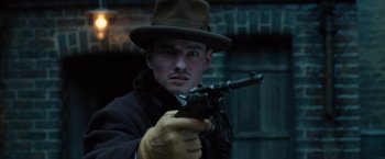 Movie still from “Wonder Woman” (2017), directed by Patty Jenkins – A man holding a gun wearing a hat and gloves; Close Up shot, Low angle