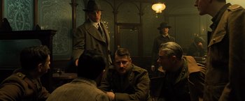 Movie still from “Wonder Woman” (2017), directed by Patty Jenkins – A group of men sitting around a table in a dimly - lit room; Medium shot, Low angle
