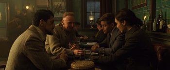Movie still from “Wonder Woman” (2017), directed by Patty Jenkins – A group of people sitting at a table with drinks; Medium shot, Over the shoulder angle