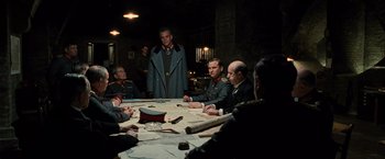 Movie still from “Wonder Woman” (2017), directed by Patty Jenkins – A group of men sitting around a table with papers on top of it; Wide shot, Low angle