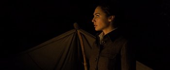 Movie still from “Wonder Woman” (2017), directed by Patty Jenkins – A woman standing in the dark holding an umbrella; Close Up shot, Over the shoulder angle
