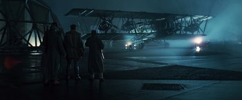 Movie still from “Wonder Woman” (2017), directed by Patty Jenkins – Two men standing in front of an airplane in the dark; Wide shot, Low angle