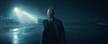 Movie still from “Wonder Woman” (2017), directed by Patty Jenkins – A man in a suit and tie standing in the dark; Medium shot, Low angle