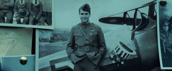 Movie still from “Wonder Woman” (2017), directed by Patty Jenkins – An old photo of a man in a military uniform standing next to an airplane; Medium shot, Low angle