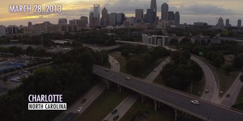 Movie still from “Woooooo! Becoming Ric Flair” (2022), directed by Ben Houser – An aerial view of a freeway and a city skyline at dusk; Extreme Wide shot, High angle