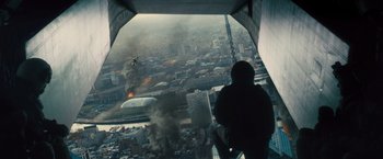 Movie still from “World War Z” (2013), directed by Marc Forster – A man standing on a ledge looking out a window at an explosion; Extreme Wide shot, High angle