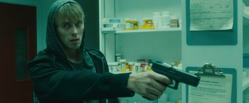 Movie still from “World War Z” (2013), directed by Marc Forster – A man holding a gun in front of a shelf of drugs; Close Up shot, Over the shoulder angle