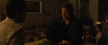 Movie still from “World War Z” (2013), directed by Marc Forster – A man sitting at a table in a living room; Medium shot, Over the shoulder angle