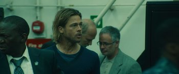 Movie still from “World War Z” (2013), directed by Marc Forster – A man standing next to another man in a room; Medium shot, Low angle