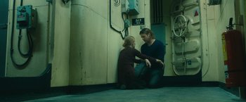 Movie still from “World War Z” (2013), directed by Marc Forster – A man and a girl sitting next to a wall; Medium shot, Low angle