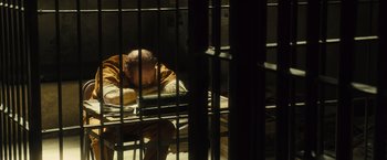 Movie still from “World War Z” (2013), directed by Marc Forster – A man sitting on a bed inside of a cage; Medium shot, High angle