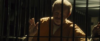 Movie still from “World War Z” (2013), directed by Marc Forster – A man in a jail cell with his hand raised; Medium shot, Over the shoulder angle