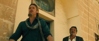 Movie still from “World War Z” (2013), directed by Marc Forster – A man standing next to another man in front of a building; Medium shot, Low angle
