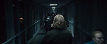 Movie still from “World War Z” (2013), directed by Marc Forster – A group of people walking down a long hallway at night; Medium shot, Over the shoulder angle