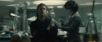 Movie still from “World War Z” (2013), directed by Marc Forster – A man and a woman are getting their arm examined by a doctor; Medium shot, Over the shoulder angle