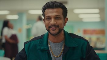 Movie still from “World's Best” (2023), directed by Roshan Sethi – A person wearing a green jacket; Close Up shot, Over the shoulder angle